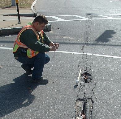Worker studying cracked pavement 